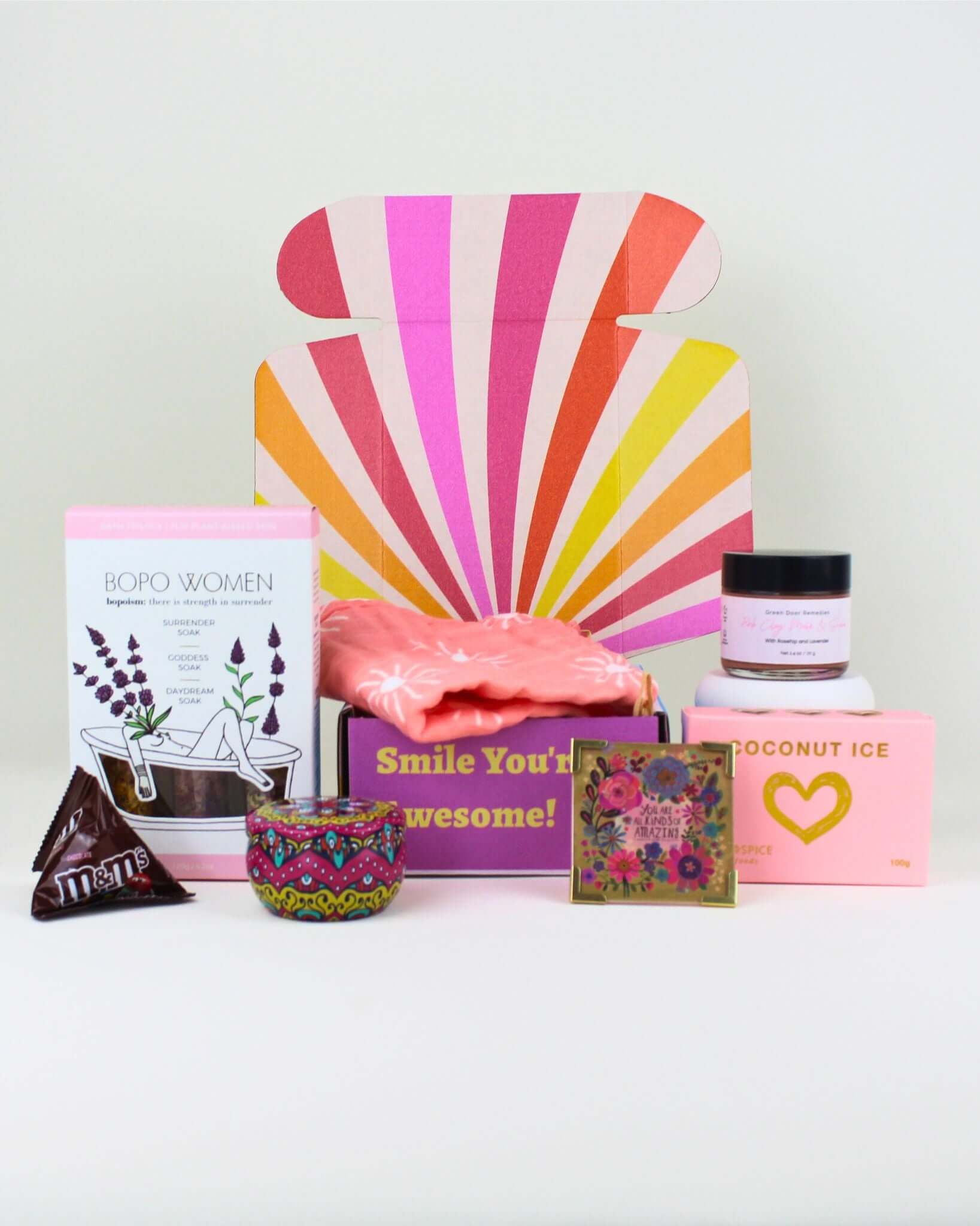 Wellness gift box NZ | Pamper box with bath salts trio, pink clay mask, cotton facecloth, hand-poured candle, keepsake magnet, M&M’s and coconut ice. A cheerful self-care gift.