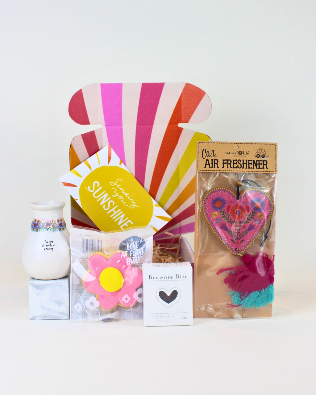 “Affordable thoughtful gift box with vase, daisy cookie, brownie, and heart air freshener.”