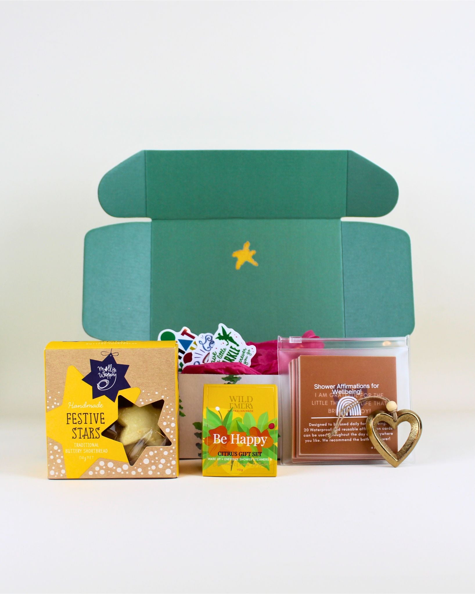 “Christmas wellness gift box with Molly Woppy cookies, waterproof shower affirmations, Wild Emery Be Happy citrus pack, shower steamers, chamomile coconut lip balm and brass Christmas keepsake.”