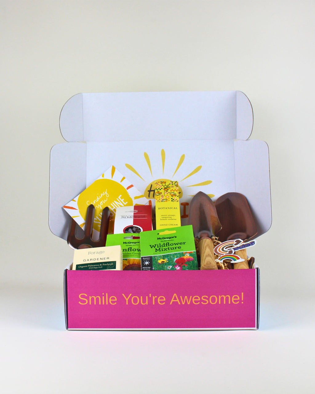 A beautifully curated gift box featuring copper garden tools, gardener’s soap, botanical hand cream, chocolate almonds, and wildflower seeds — a thoughtful present for green-thumbed friends.