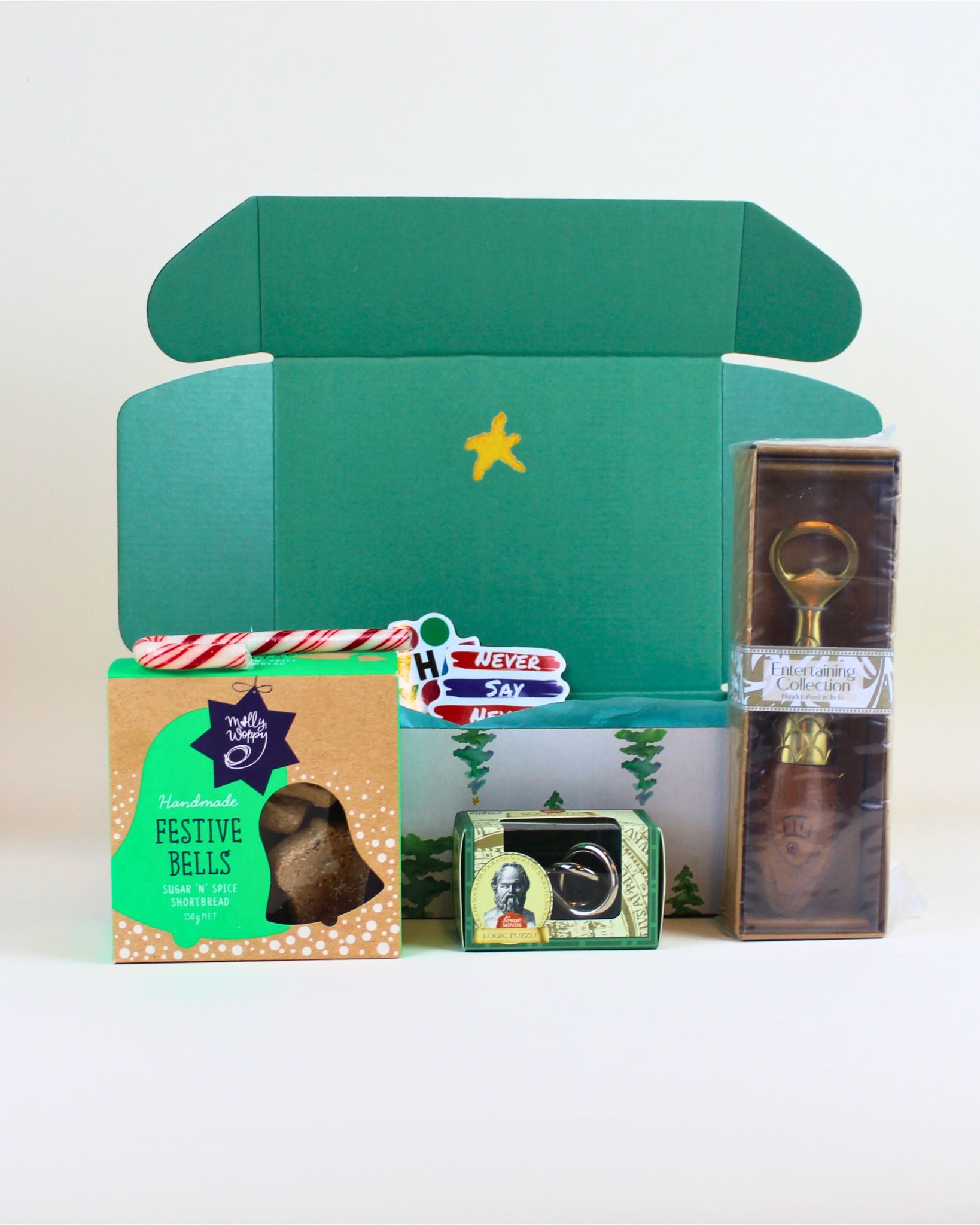 “Budget-friendly Christmas gift box with Molly Woppy cookies, handcrafted brass bottle opener with wooden fish citrus juicer, and tinker puzzle.”