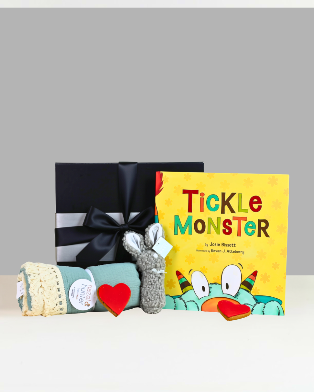 Hello Little One Baby Gift Box NZ with Tickle Monster book, bunny rattle, cotton baby throw, gingerbread hearts and personalised card in a premium black magnetic gift box.