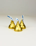 Hershey's kisses with blue and white striped sticks on a light gray background