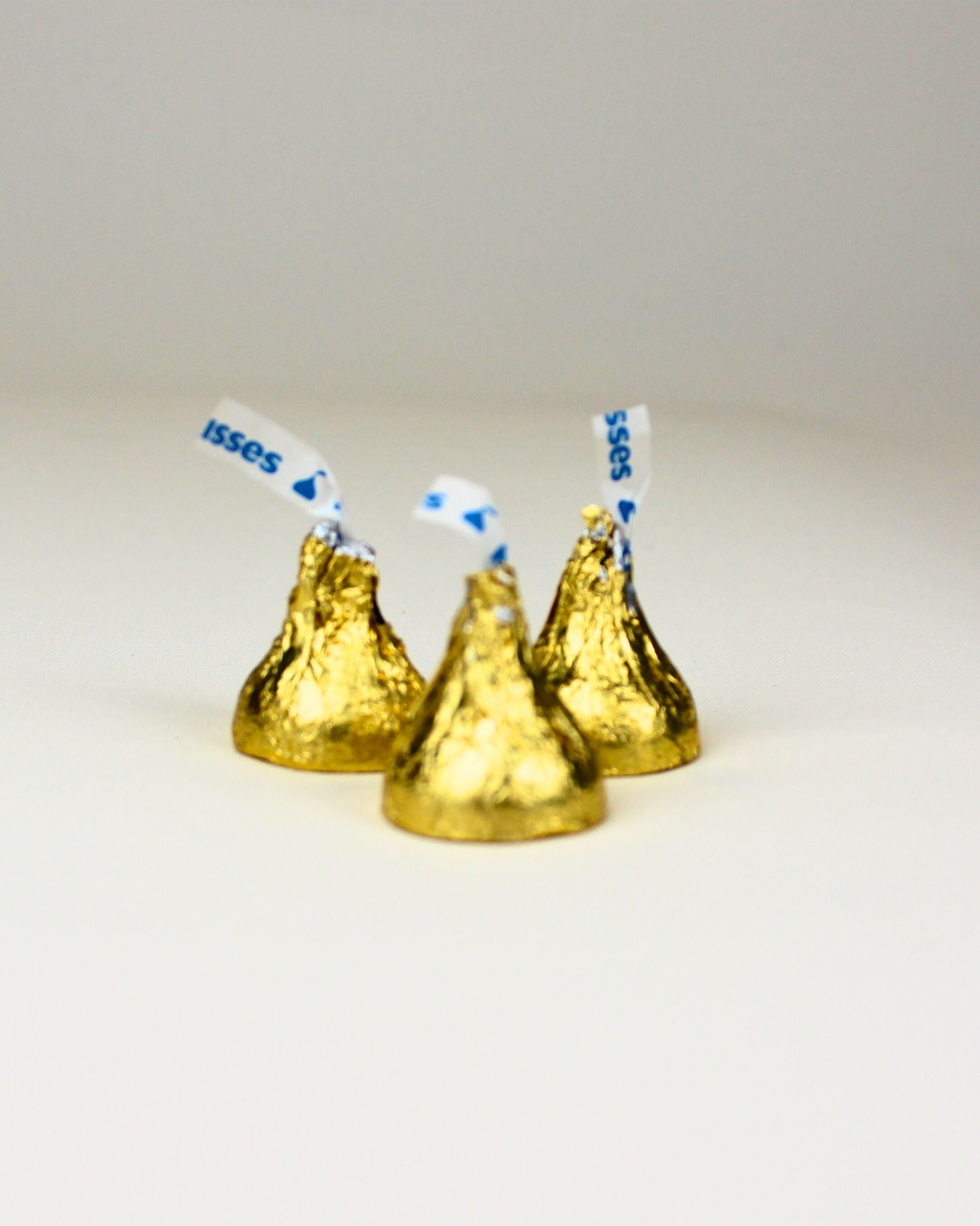 Hershey's kisses with blue and white striped sticks on a light gray background
