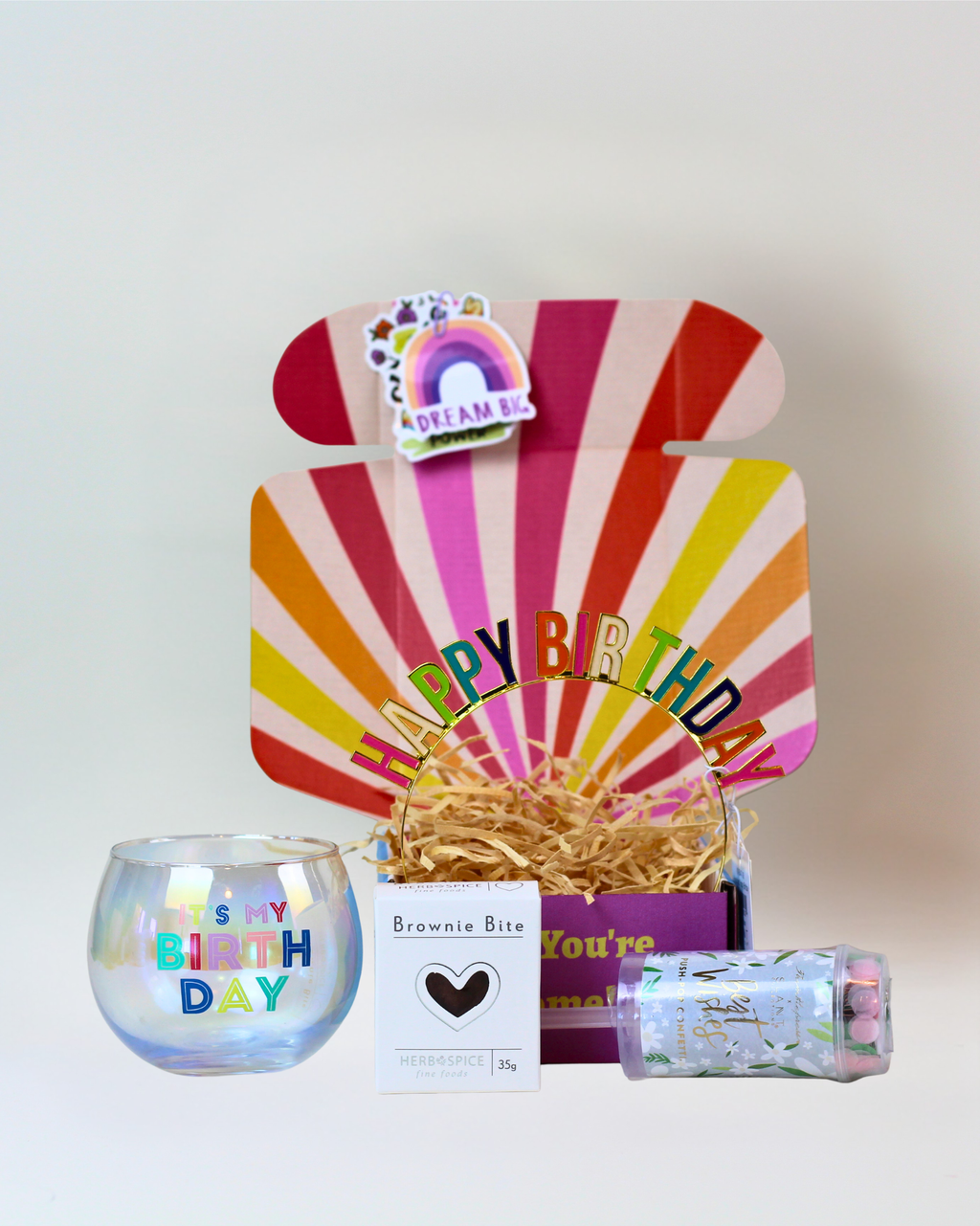 Little Birthday Gift Box NZ featuring a Happy Birthday roly poly glass, metal birthday headband, chocolate brownie bite, party popper, and personalised gift card, beautifully packaged for gifting.