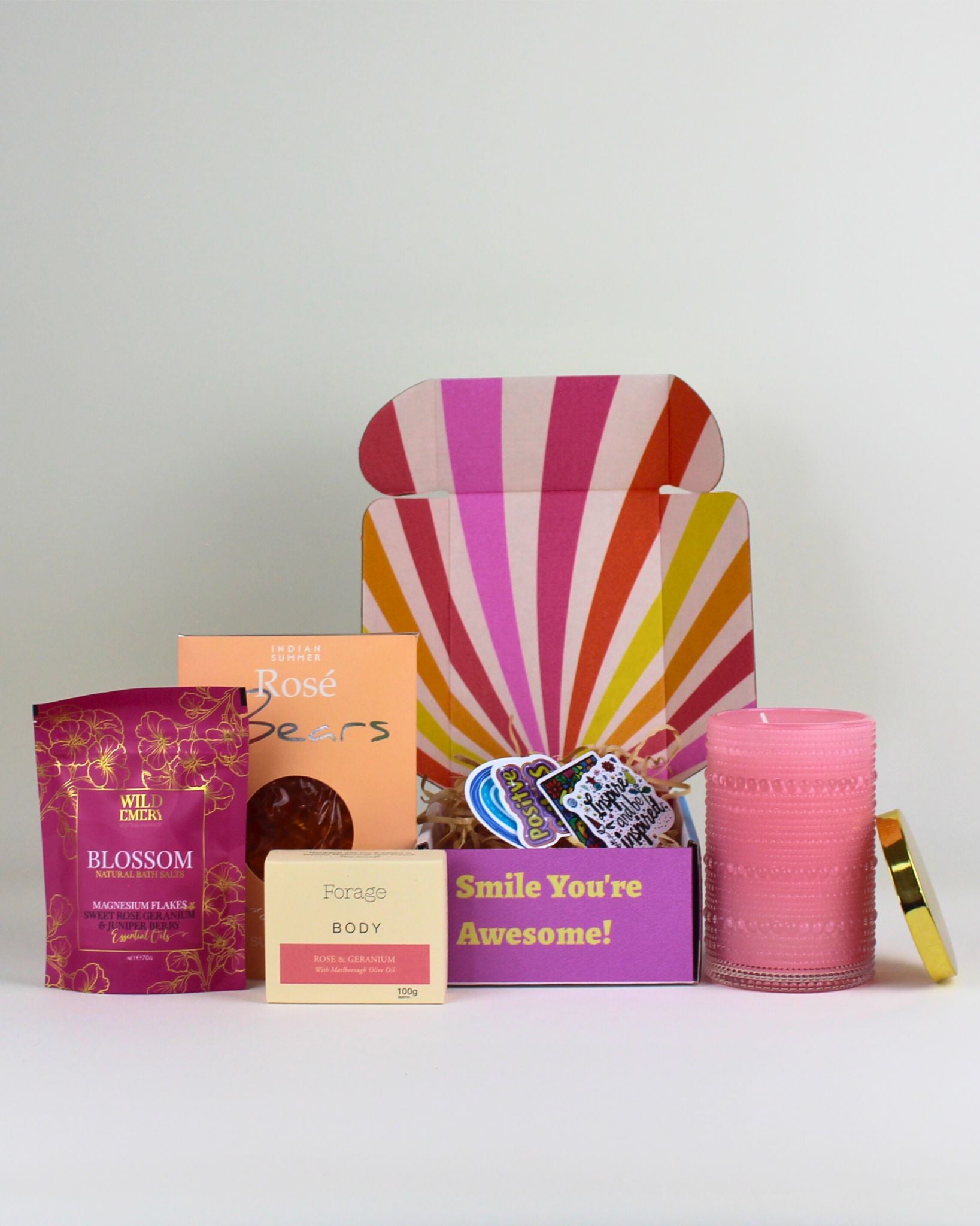 A luxury wellness gift box for her featuring a pink scented candle, bath salts, natural body bar and indulgent treats.