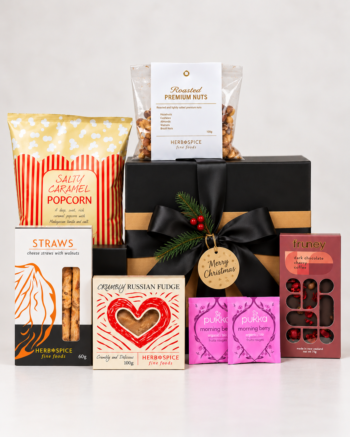 Merry Christmas staff appreciation gift box NZ featuring roasted nuts, salted caramel popcorn, Pukka berry tea, walnut and cheese straws, crumbly Russian fudge and Fruney cherry and coffee dark chocolate in a premium black magnetic gift box with ribbon.

