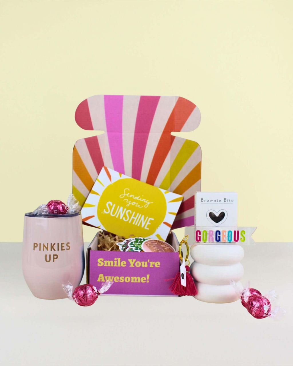 Birthday Gifts NZ sunshine celebration gift box with pink wine tumbler, “Cheers Gorgeous” keyring, brownie, strawberry Lindor chocolates, and positive affirmation cards. 