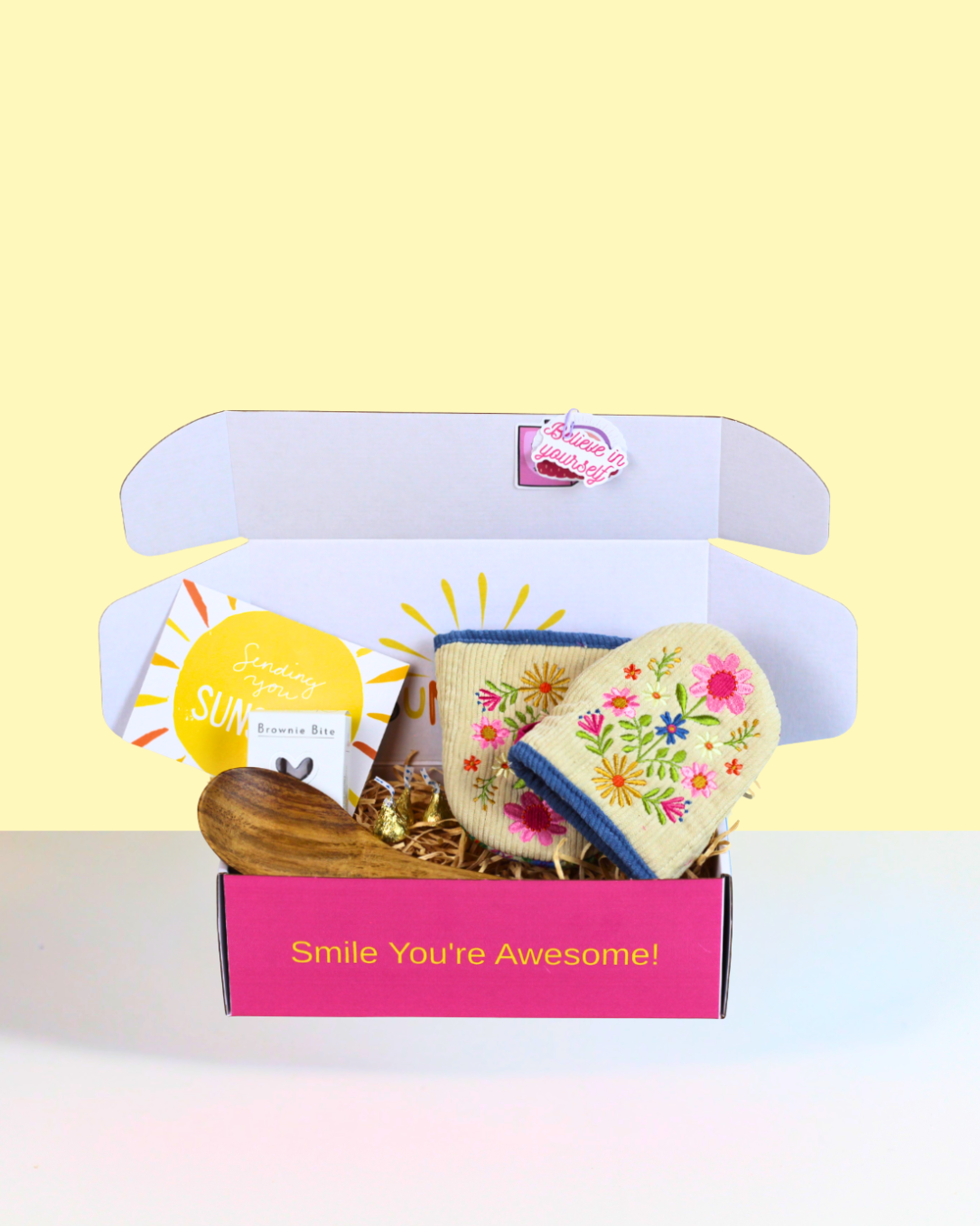 The Star Baker Gift Box NZ featuring floral embroidered oven mitts, wooden spoon, Herb & Spice Fine Foods chocolate brownie mix, Hershey's Kisses and a personalised card in A Box-Full's signature Sunshine Gift Box.