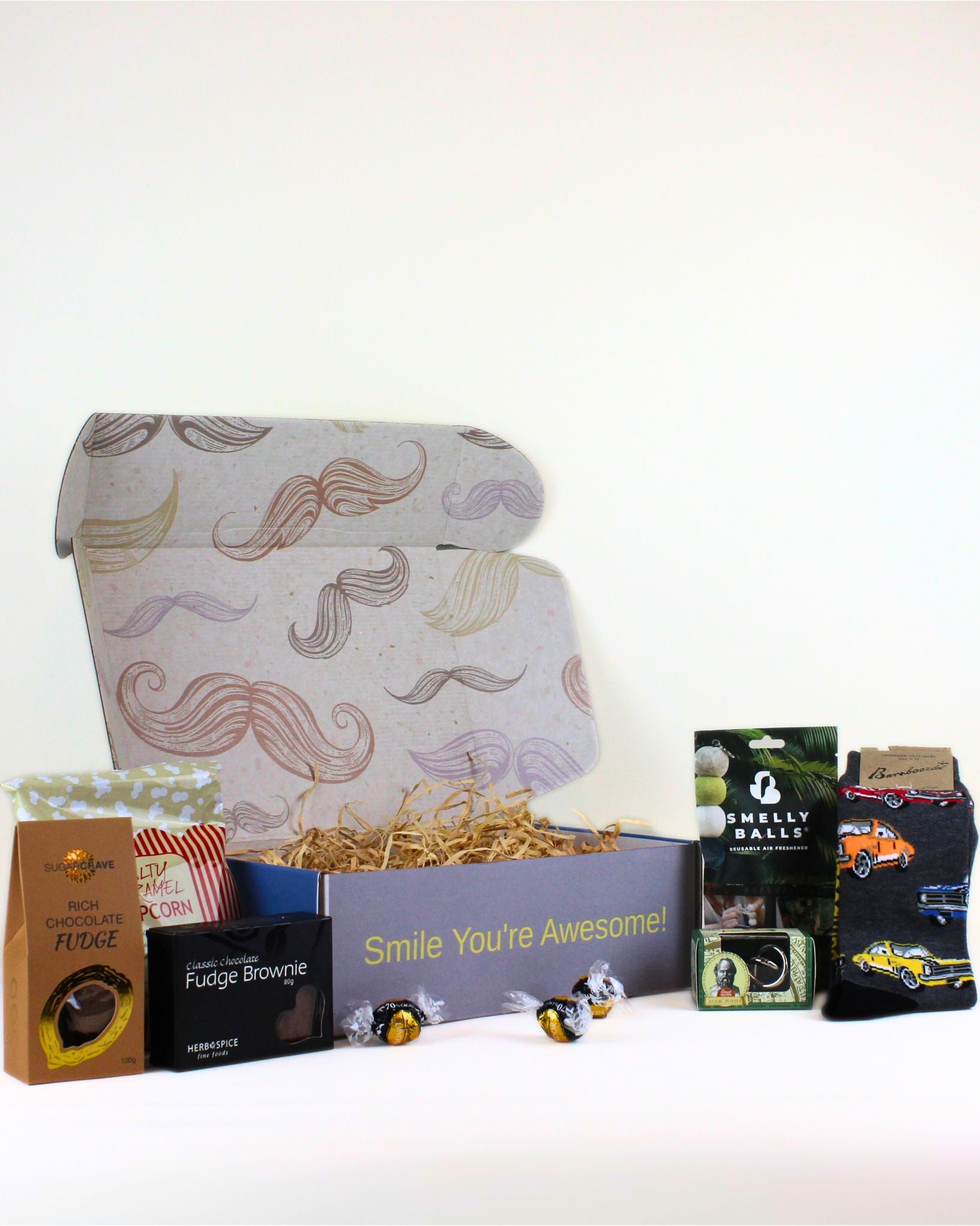 Unique gift box for him featuring Bamboozled car socks, Smelly Balls car air freshener, Socrates logic puzzle, rich fudge, brownie, popcorn and Lindor chocolates.