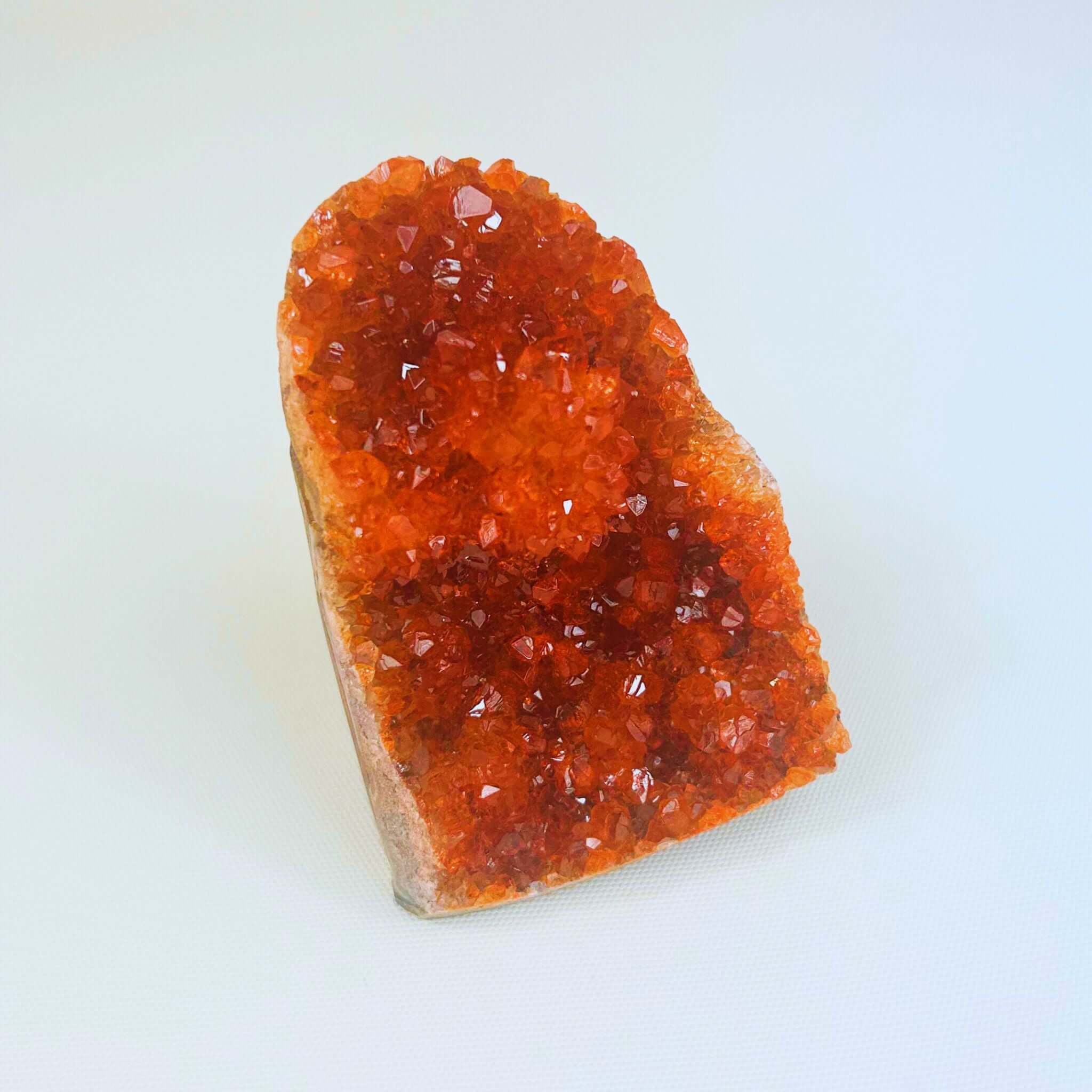 Orange crystal cluster displayed on a white surface, ideal for unique crystal gifts New Zealand.